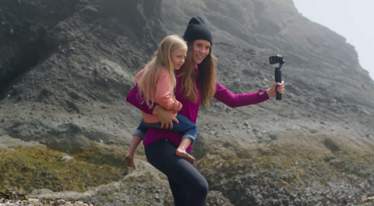 A little girl standing in front of a rocky hill